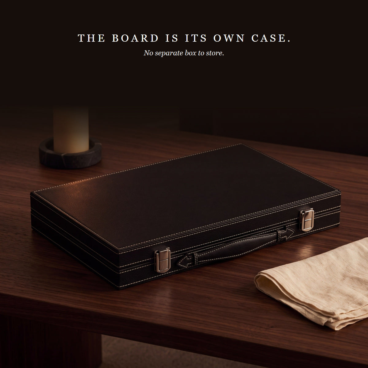 Folding Backgammon Deep Black closed on a walnut table beside a candle